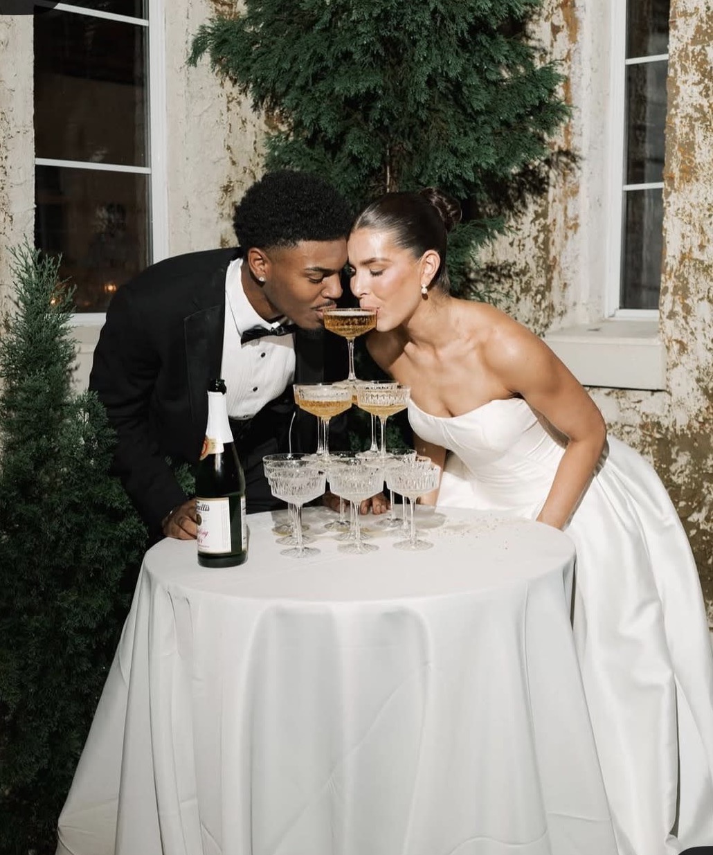 Bride and groom sipping from the top of a champagne tower