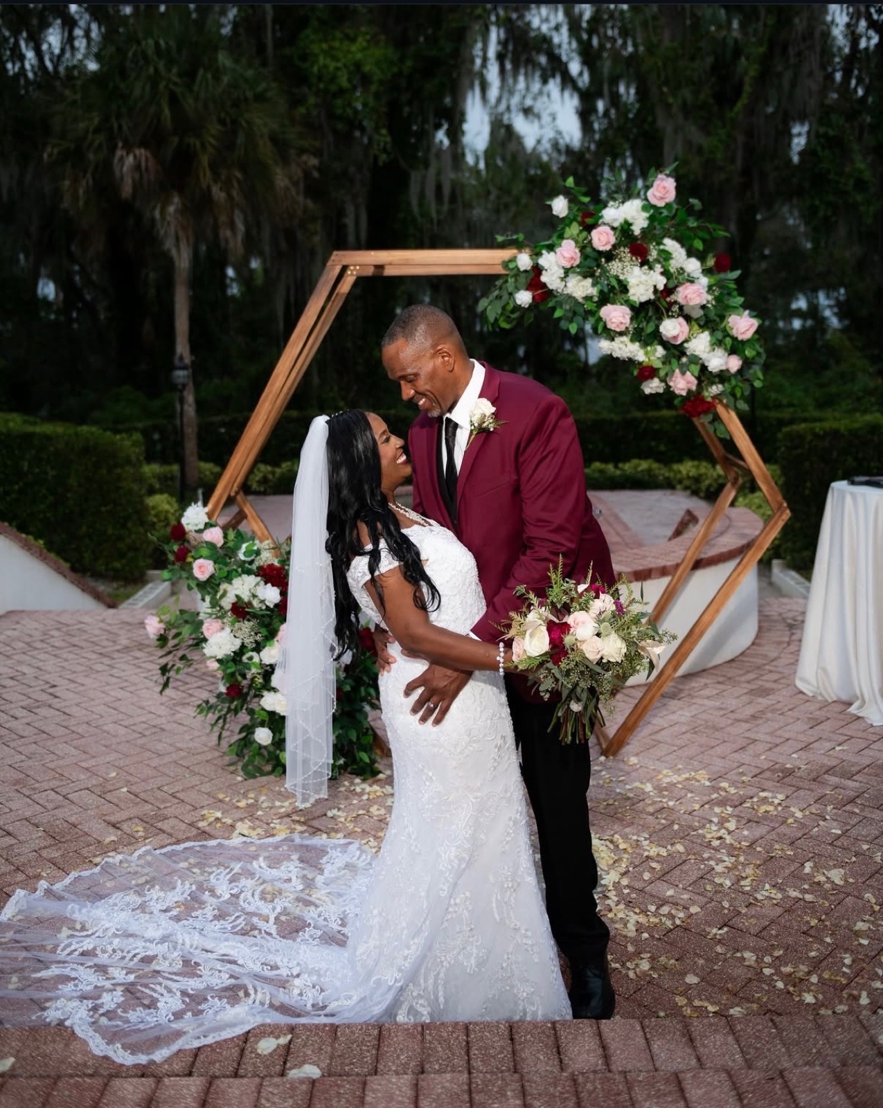 Bride and groom embracing in front of the floral hexagon arch