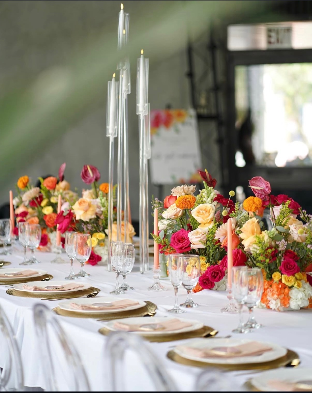 Long table with bright florals, crystal candelabras and gold chargers