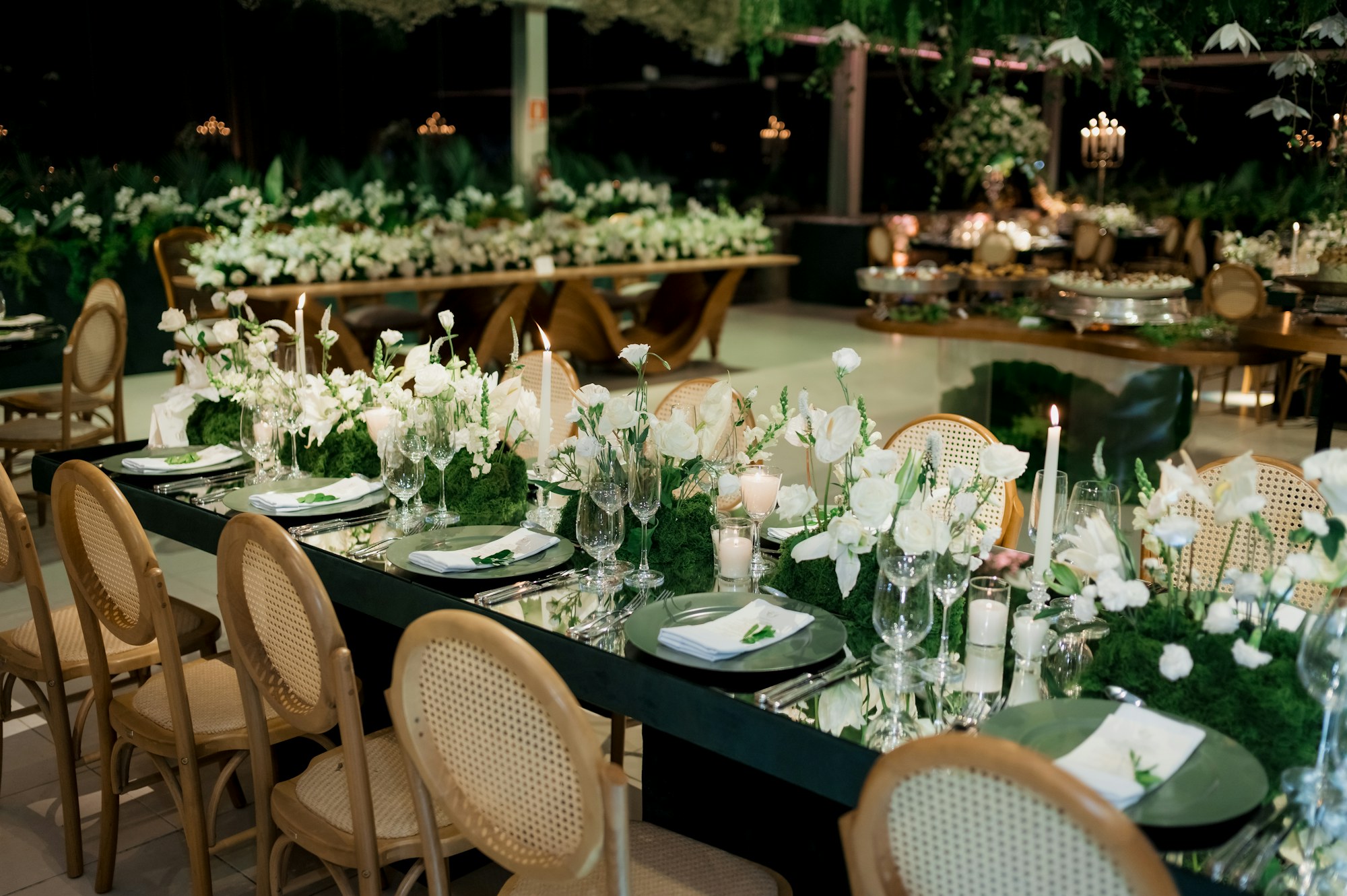 Reception with black tables, white florals and cane-back chairs